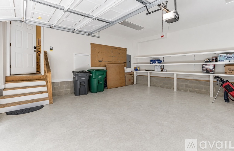 A spacious garage with a white ceiling, a staircase, and a golf bag.