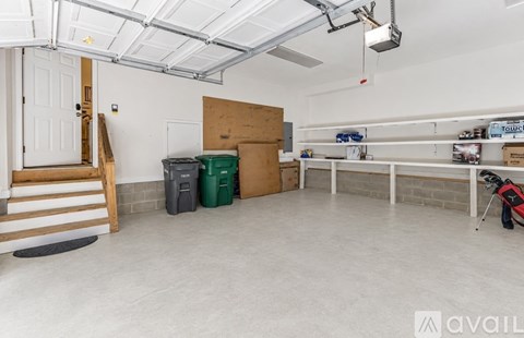 A spacious garage with a white ceiling, a staircase, and a golf bag.
