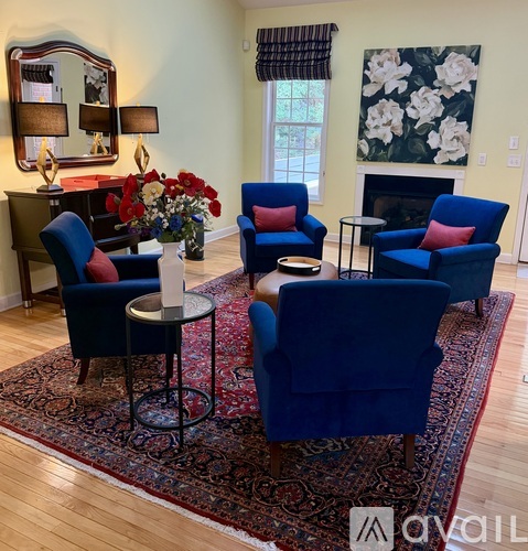 A living room with blue chairs and a vase of flowers.