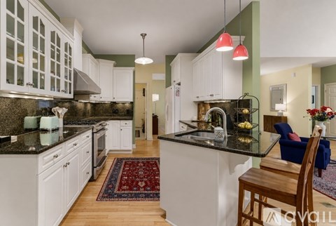 A kitchen with white cabinets and a black countertop.
