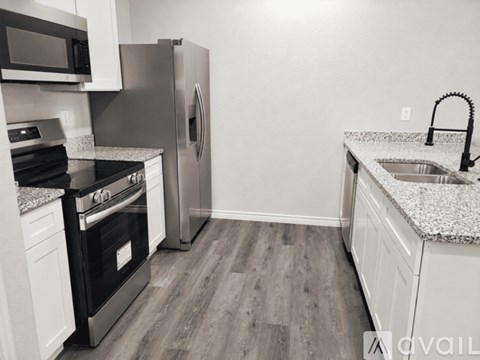 A kitchen with a stove, refrigerator, and microwave.