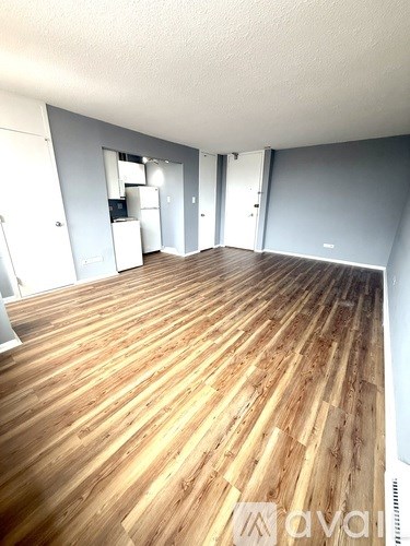 A spacious room with wooden flooring and white walls.