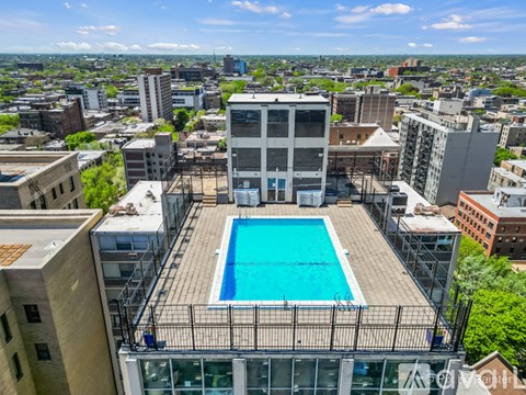 A rooftop pool is surrounded by a metal fence.