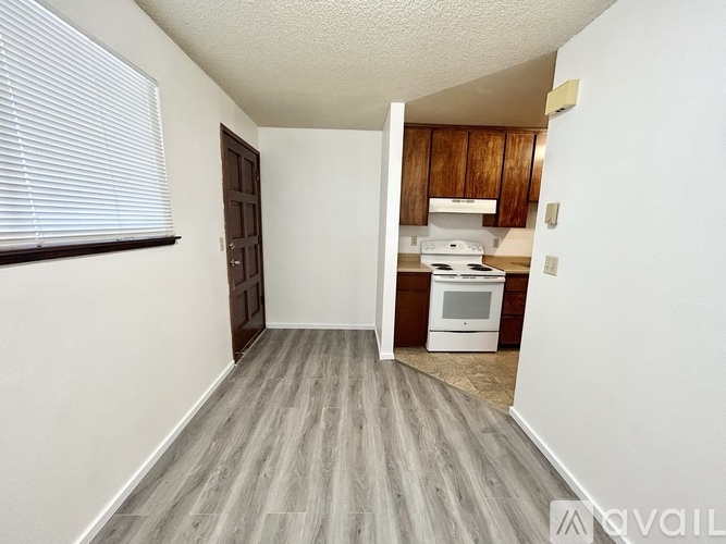 A kitchen area with a white stove top oven and wooden cabinets.