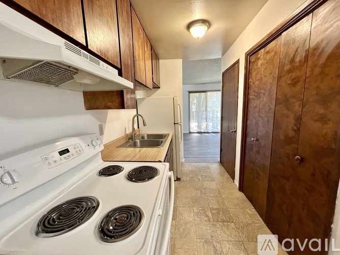 A kitchen with a white stove top oven and wooden cabinets.