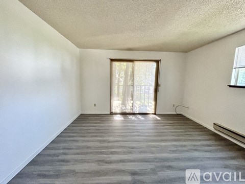A spacious room with a grey floor and a window with curtains.