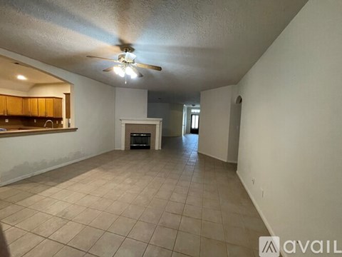 A spacious room with a ceiling fan and tiled floor.