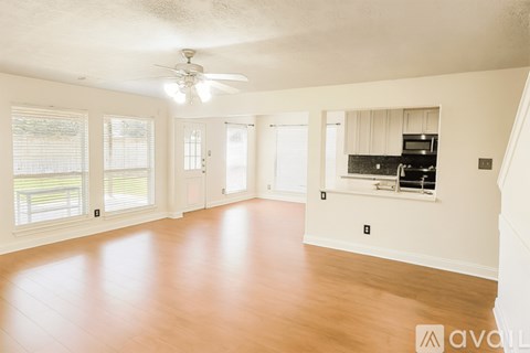 A spacious room with wooden floors and a ceiling fan.