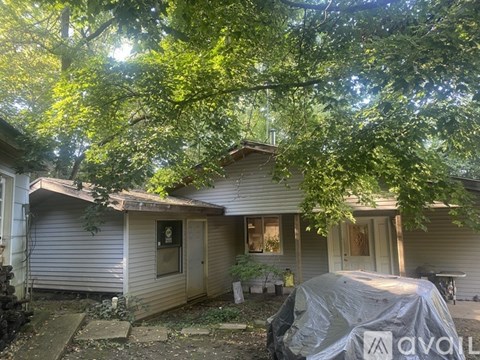 A house with a covered patio and a tree in front.