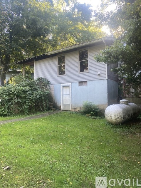 A house with a white door and windows surrounded by greenery.