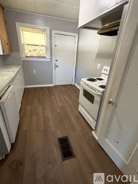 A kitchen with a white oven and wooden floors.