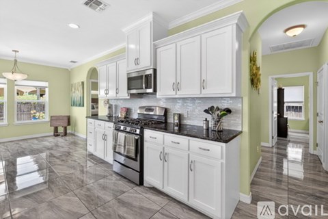 A kitchen with white cabinets and a black stove top oven.