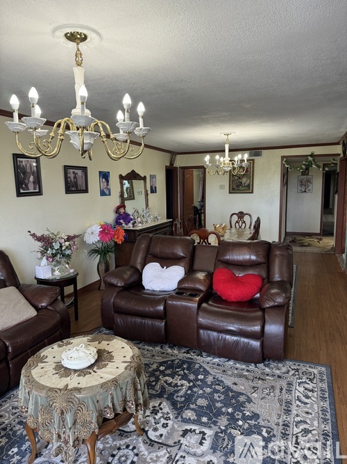 A living room with a brown leather couch and a chandelier.