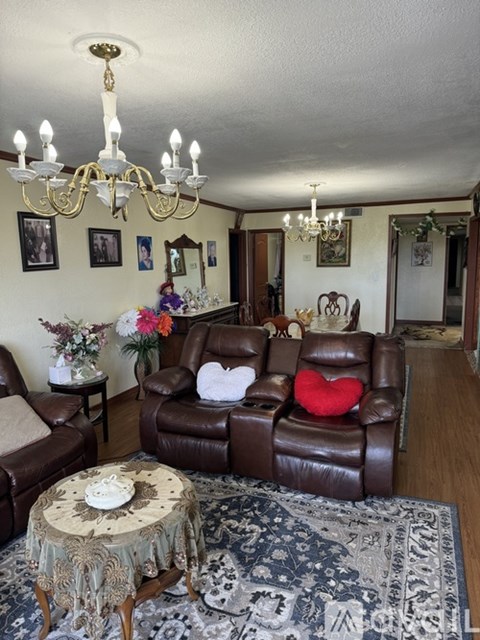 A living room with a brown leather couch and a chandelier.