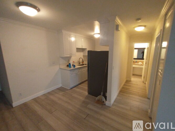 A kitchen area with a black refrigerator and wooden flooring.