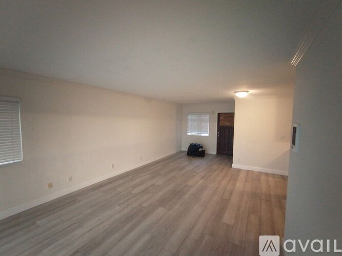 A room with wooden flooring and a window with blinds.