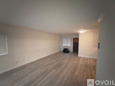 A room with wooden flooring and a window with blinds.