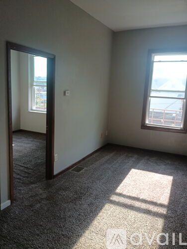 A room with a carpet floor, a door, and a window.