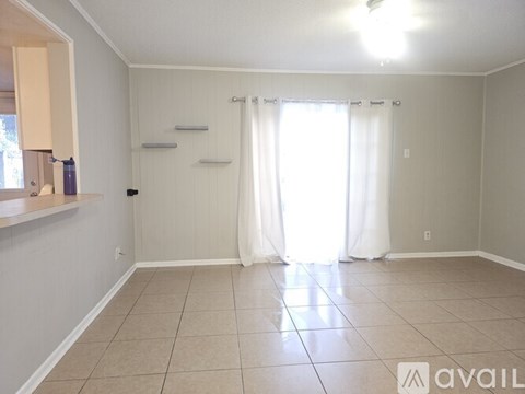 A room with a window covered by white curtains and a tiled floor.