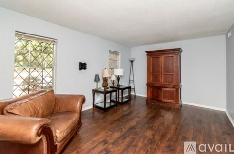 A living room with a brown leather couch and a wooden cabinet.