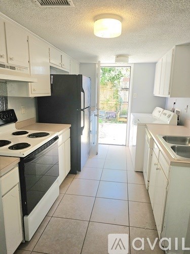 A kitchen with white cabinets and a black refrigerator.