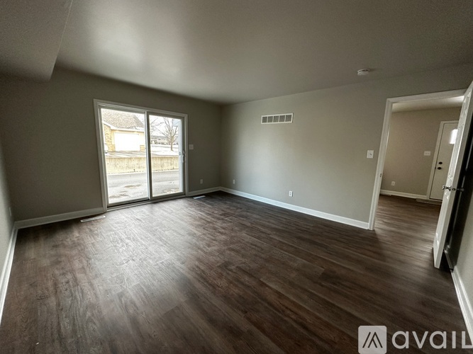 A spacious room with wood flooring and sliding glass doors.