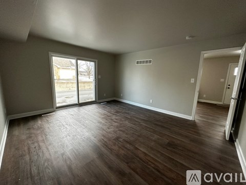A spacious room with wood flooring and sliding glass doors.