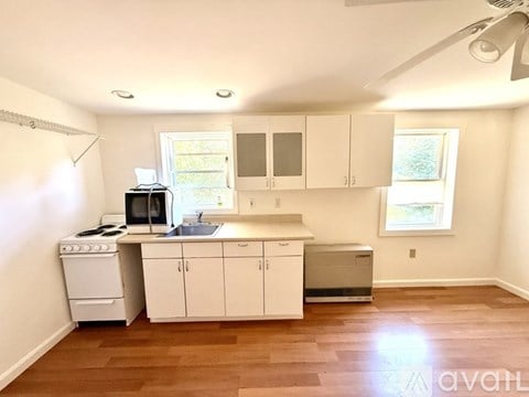 A kitchen with white cabinets and a wooden floor.