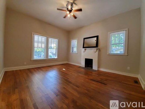 A spacious room with wood flooring and a fireplace.
