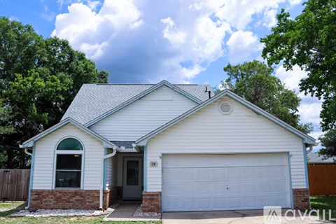 A house with a white garage door and a brick pillar.