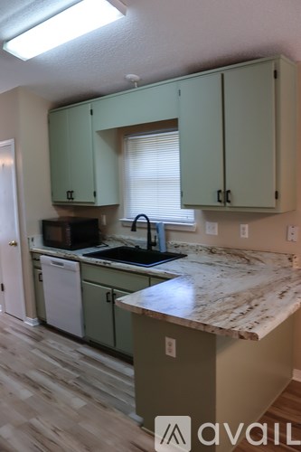 A kitchen with green cabinets and a marble countertop.