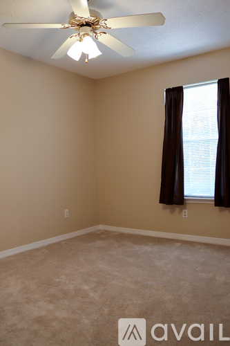 A room with a ceiling fan and a window with black curtains.