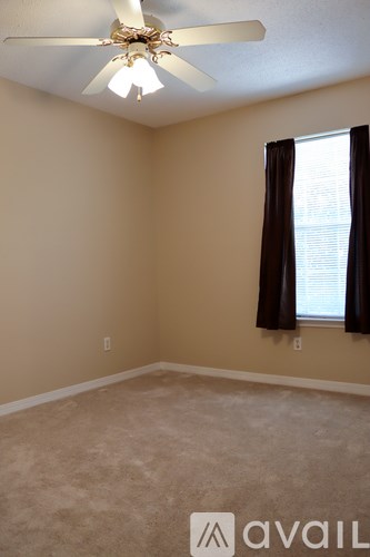 A room with a ceiling fan and a window with black curtains.