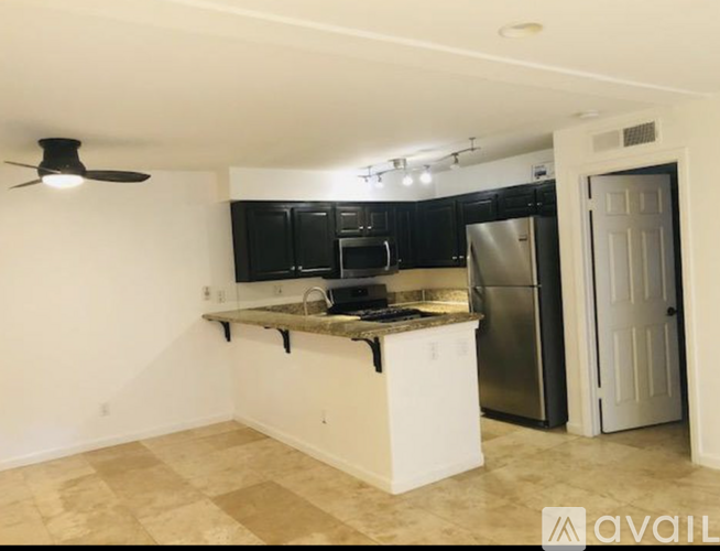 A kitchen with black cabinets and a white island.