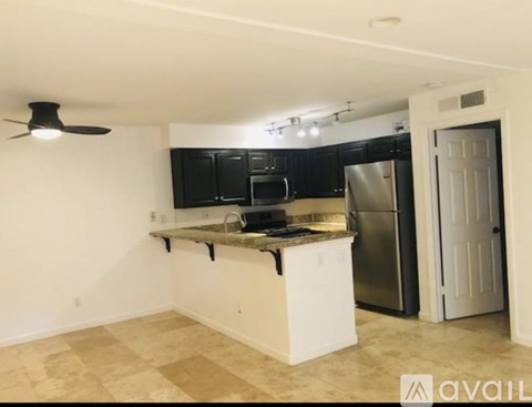 A kitchen with black cabinets and a white island.