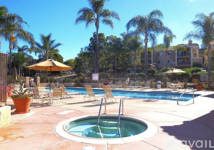 A pool area with a hot tub and chairs.