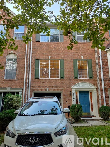 A white car is parked in front of a red brick house.