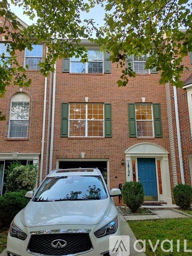 A white car is parked in front of a red brick house.