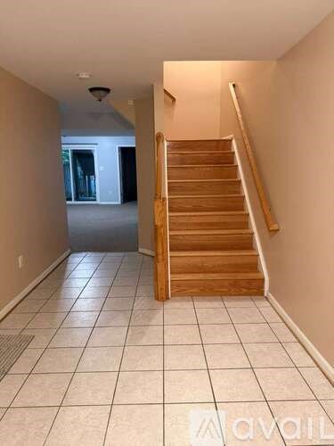 A wooden staircase with a tiled floor leading to a doorway.