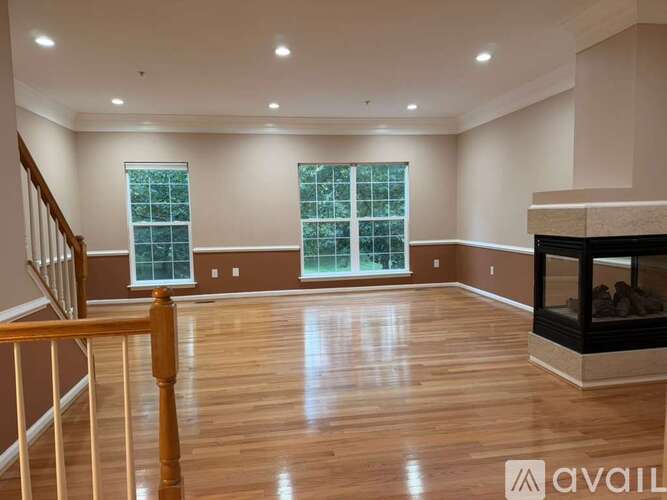 A spacious living room with wood flooring and a fireplace.