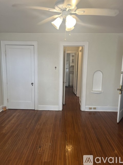 A room with a white ceiling fan and wooden floors.