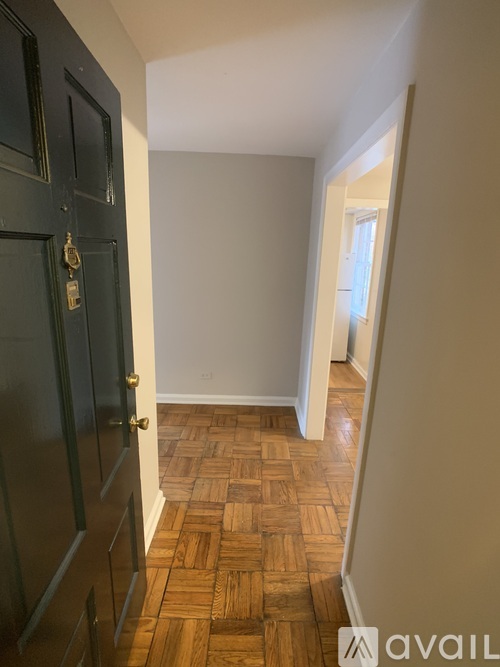 A hallway with a wooden floor and a black door.