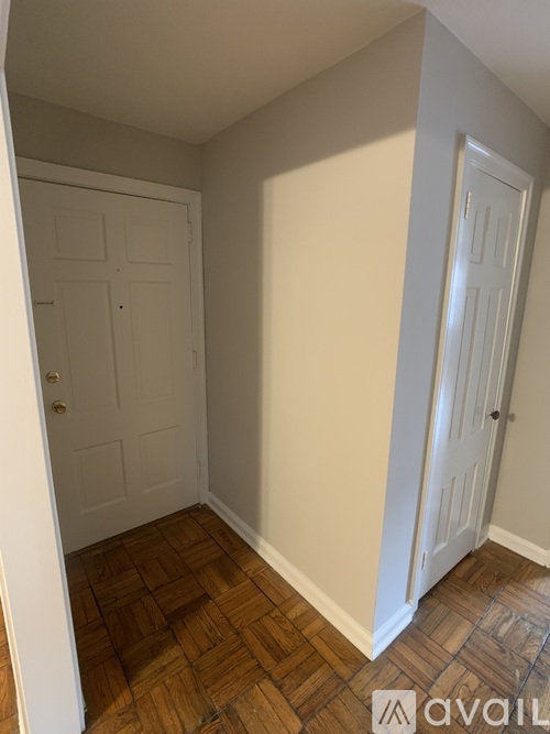 A room with a white door and a wooden floor.