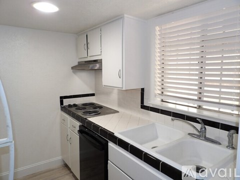 A kitchen with white cabinets and black appliances.