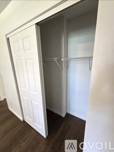 A white closet door is open with a shelf and rod.