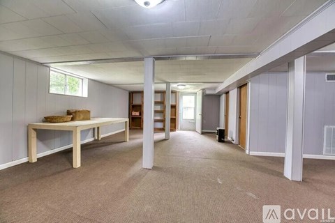 A spacious room with a long table and chairs, carpeted floor, and white walls.