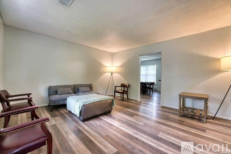 A bedroom with a bed, a chair, and a nightstand.