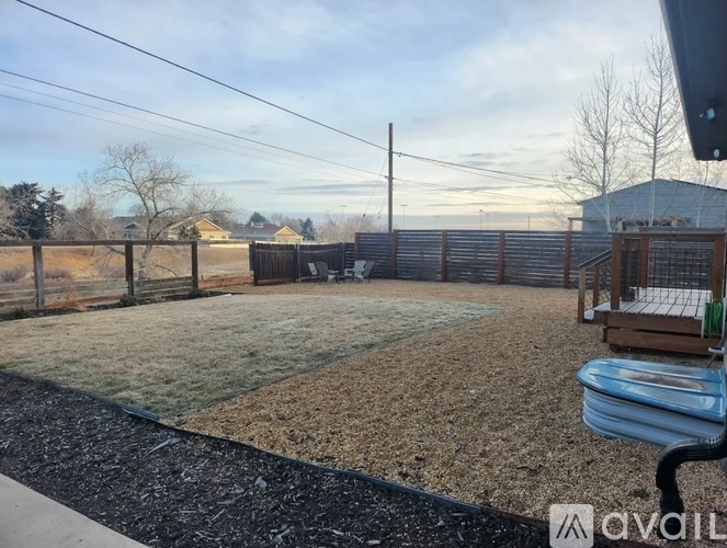 A backyard with a fence, a hot tub, and a gravel area.
