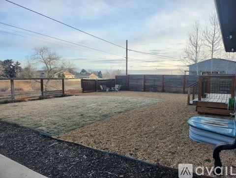 A backyard with a fence, a hot tub, and a gravel area.