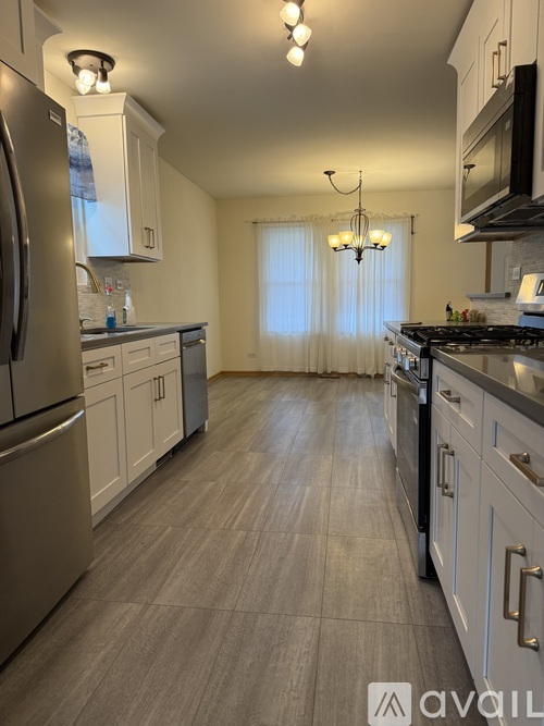 A kitchen with a refrigerator, cabinets, and a stove top oven.